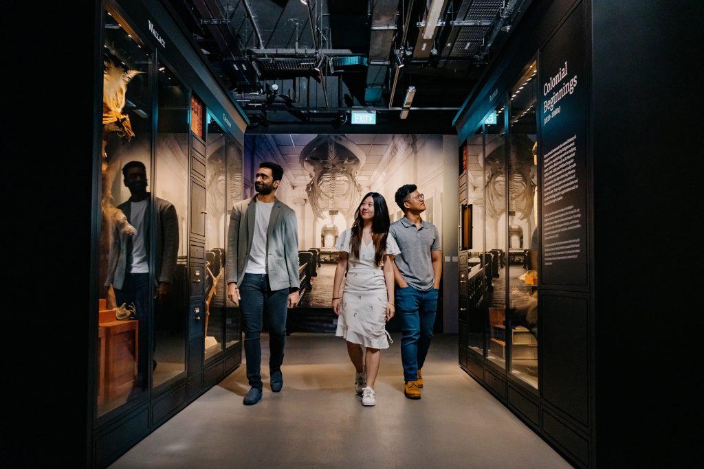 Three visitors walking through the Heritage Gallery and looking at the displays.